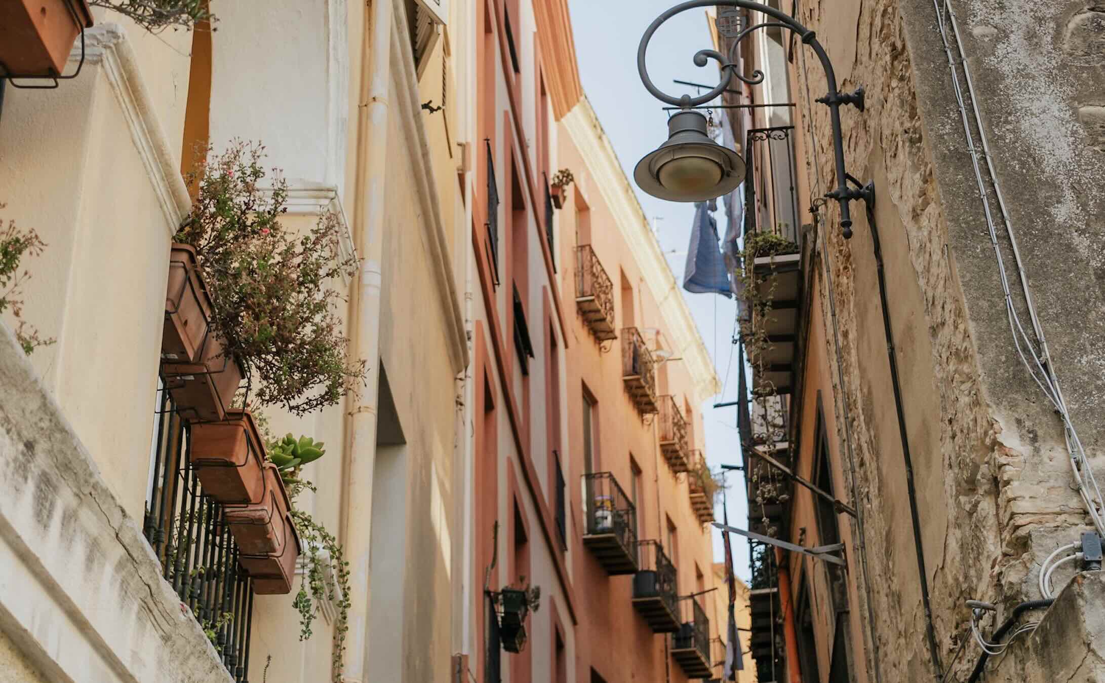 Many Cagliari streets are narrow, steep, and often cobblestoned, running between tall medieval buildings of pale golden limestone.