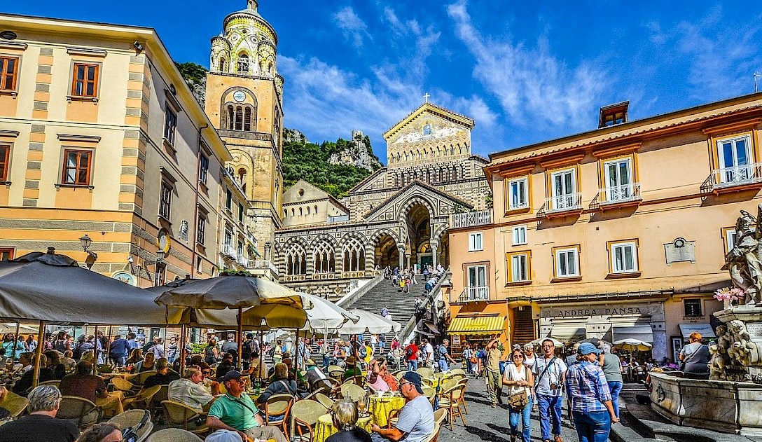 A bustling ohoto of an outdoor cafe next to a historic church in Europe as one of many beautiful landscapes enjoyed by travelers in Tours of Distinction's group tours for seniors.